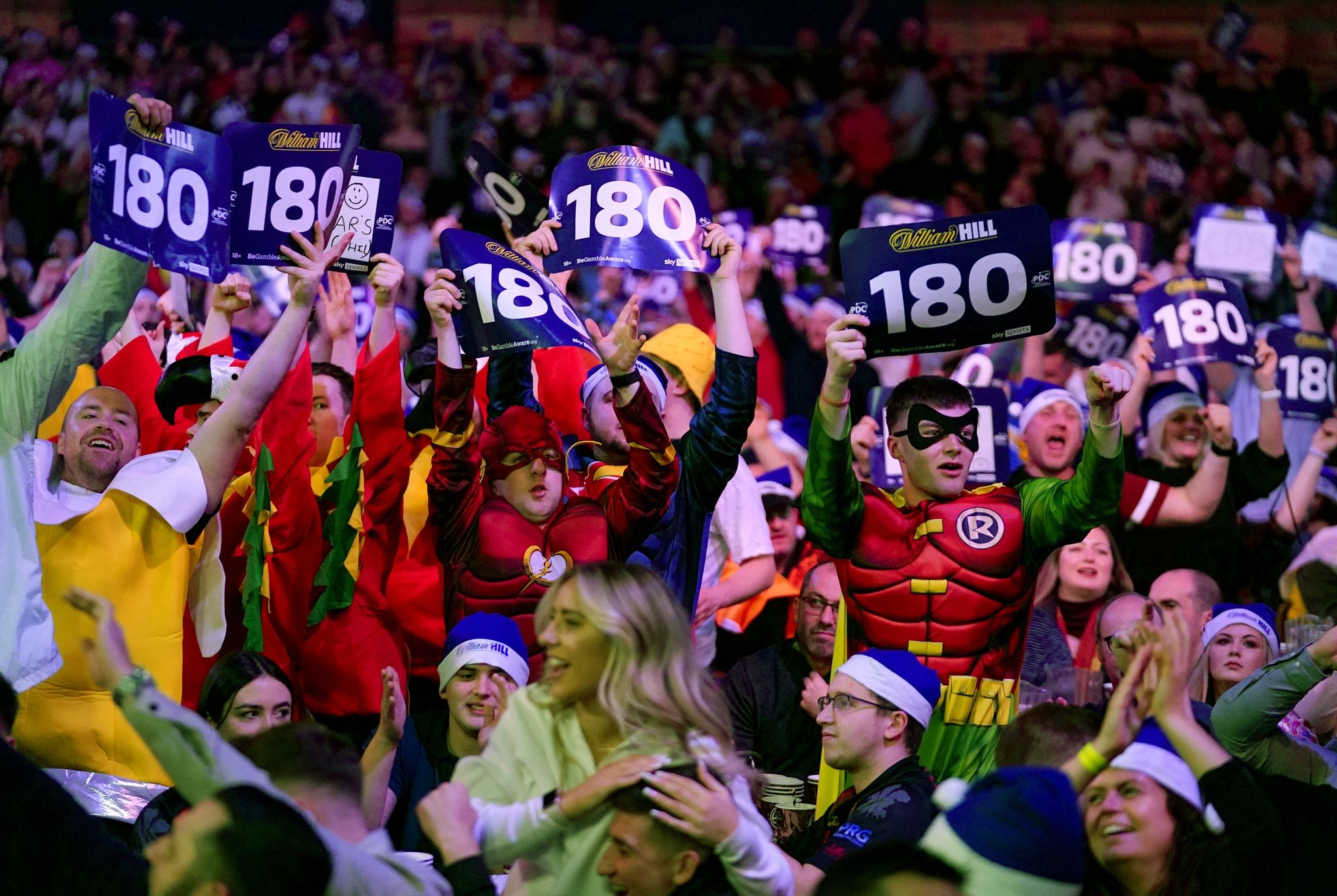 Fans in Kostümen mit 180-Schildern während einer Partie im Alexandra Palace.