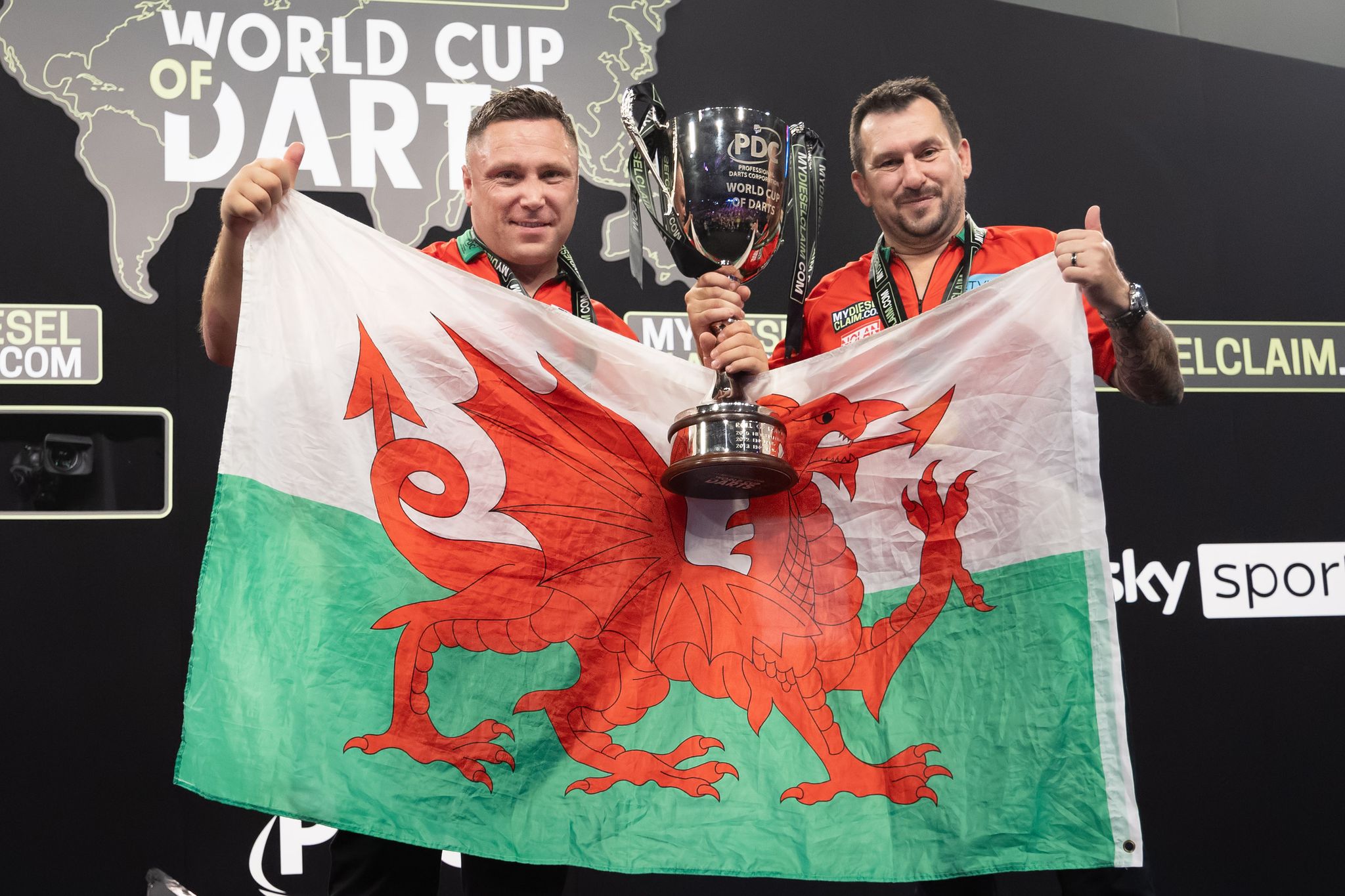 Die Waliser Darts-Spieler Gerwyn Price (l) und Jonny Clayton feiern den Sieg bei der Team-WM.