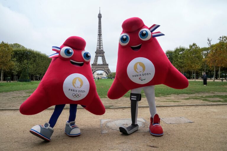 Die Maskottchen der Olympischen (l) und Paralympischen Spiele in Paris stehen vor dem Eiffelturm.