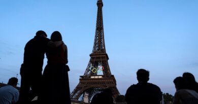 Paris-Touristen vor dem mit den olympischen Ringen geschmückten Eiffelturm.
