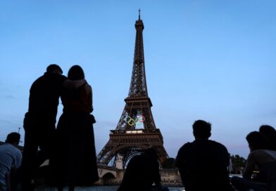 Paris-Touristen vor dem mit den olympischen Ringen geschmückten Eiffelturm.