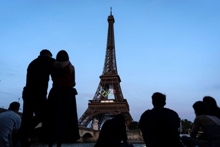 Paris-Touristen vor dem mit den olympischen Ringen geschmückten Eiffelturm.