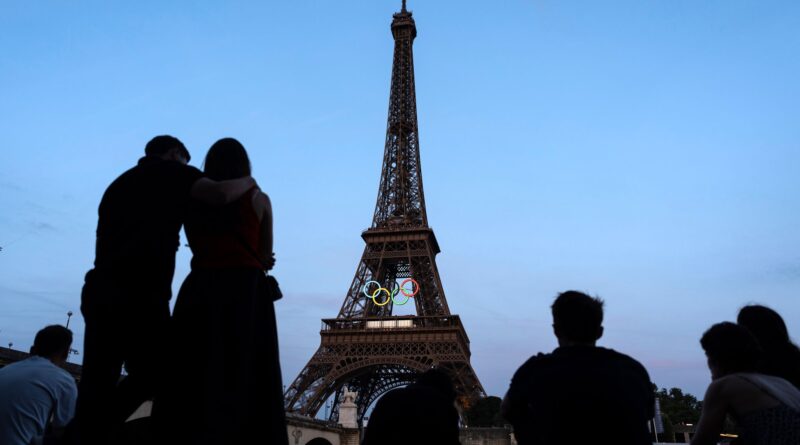 Paris-Touristen vor dem mit den olympischen Ringen geschmückten Eiffelturm.