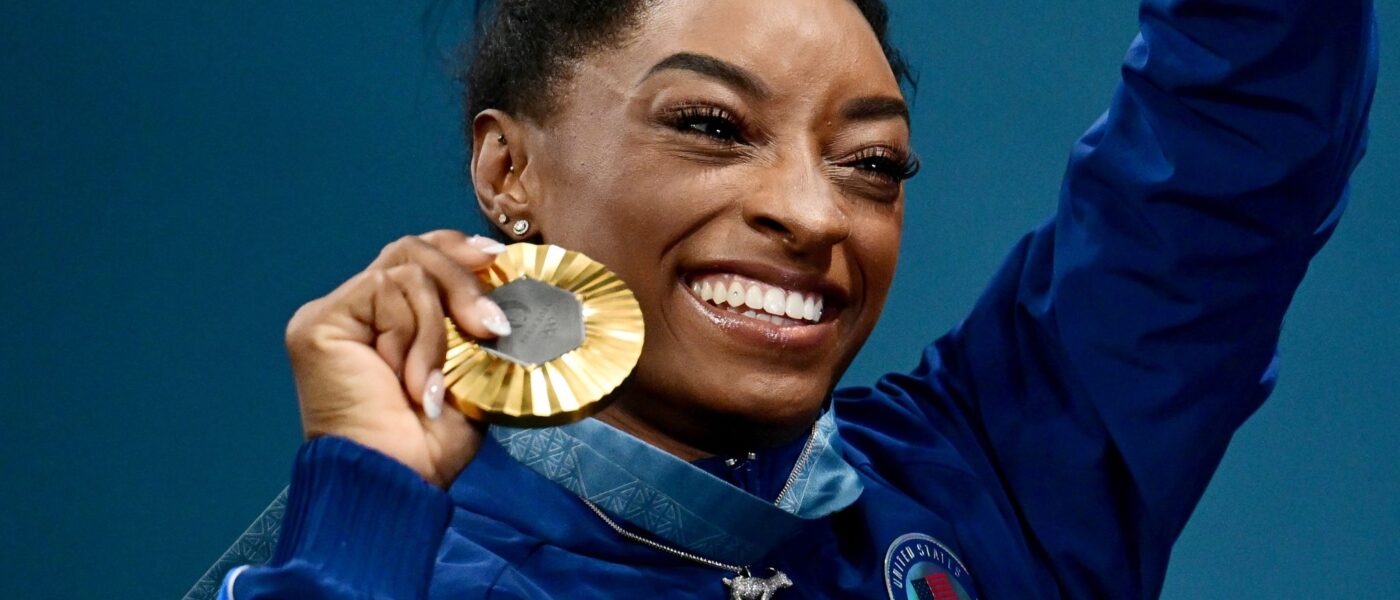 Simone Biles zeigt stolz ihre sechste olympische Goldmedaille.