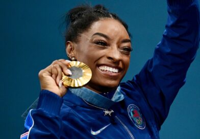 Simone Biles zeigt stolz ihre sechste olympische Goldmedaille.