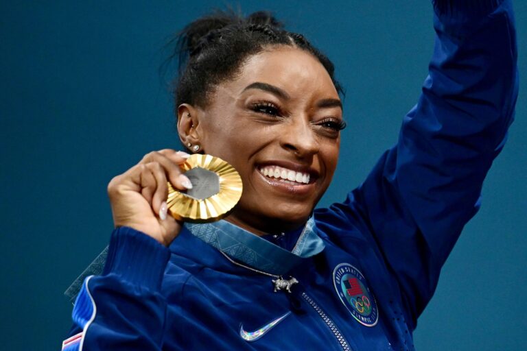 Simone Biles zeigt stolz ihre sechste olympische Goldmedaille.